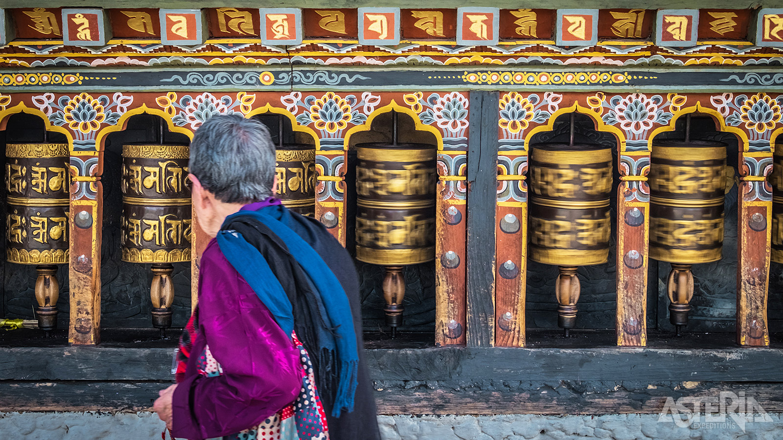 Typische gebedsmolens in een kleurrijk beschilderd kader naast een tempel in Bhutan