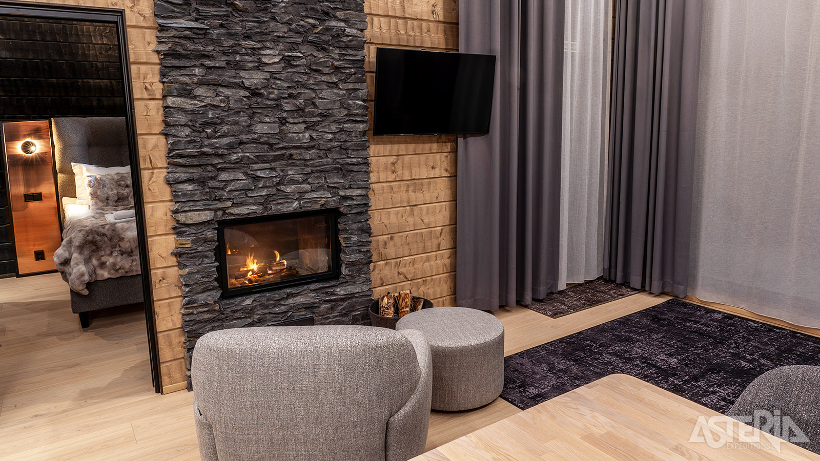 In de leefruimte van een Lumo Lakeside Lodge is een gezellig haardvuur voorzien