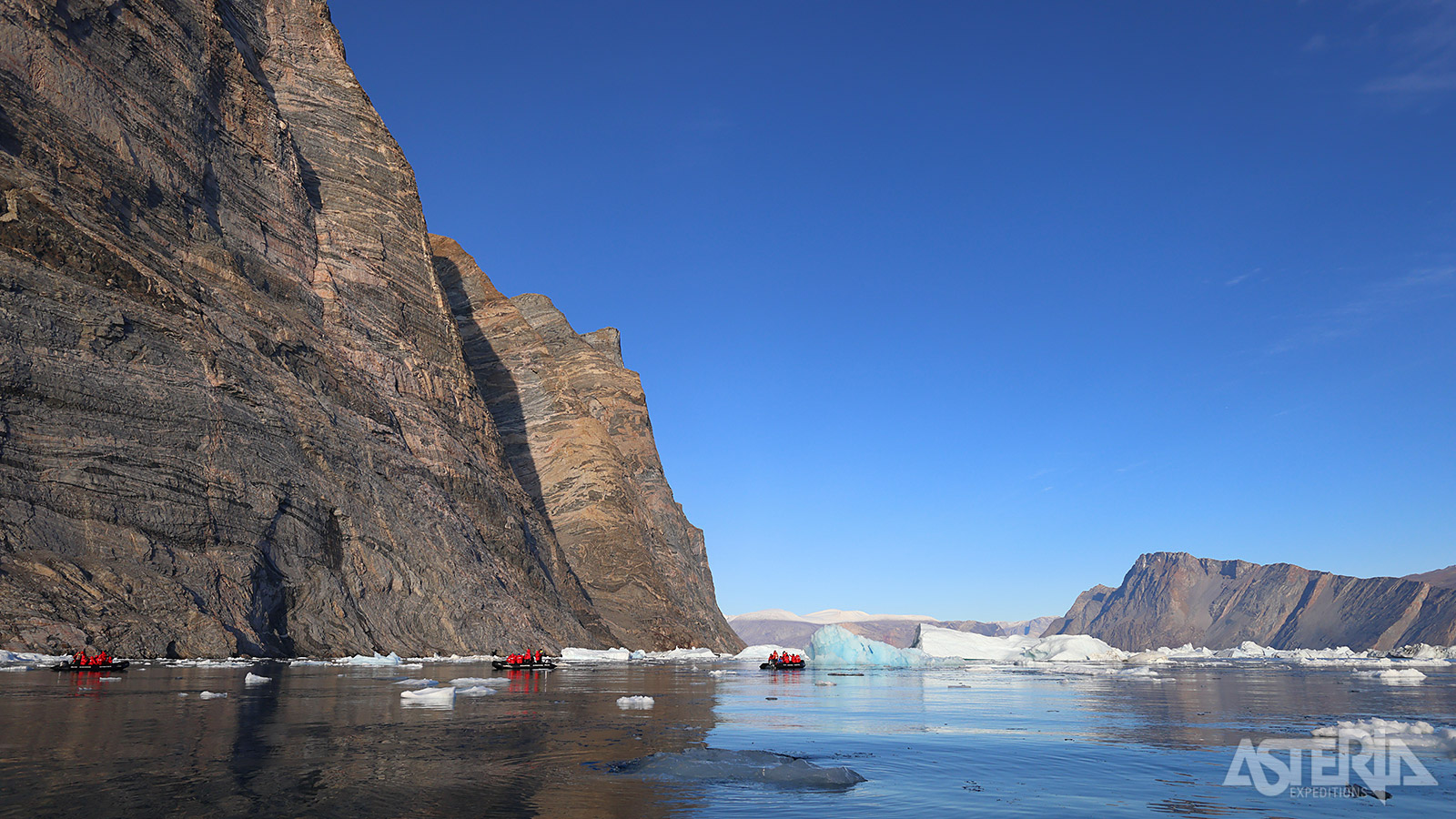 Torenhoge kliffen met steile wanden vormen een spectaculair contrast vormen met het glinsterende fjordwater