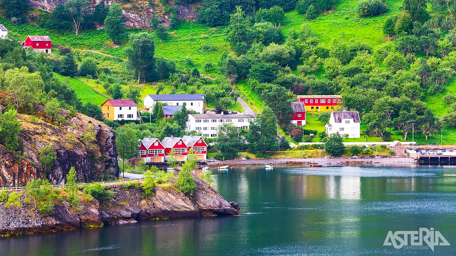 Kleurrijke houten huisjes in Flåm, omringd door steile bergen en diepe fjorden